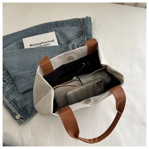 Detail view of canvas bucket bag interior with magnetic clasp and brown leather handle