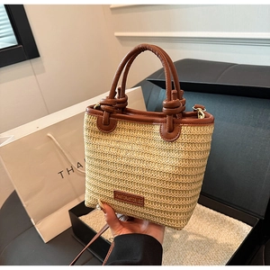 Detailaufnahme der Stroh-Eimertasche mit dunkelbraunem Lederbesatz und Gold-Hardware
