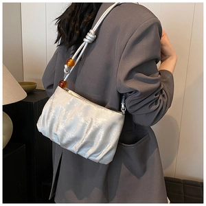 Bolso de nube plisado plateado con detalle de cuentas de ámbar usado por modelo