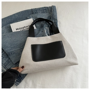 Detail of minimalist cream canvas bucket bag with black leather pocket and wide handle