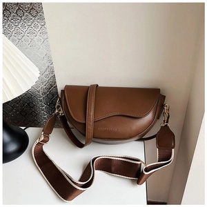 Close-up of a brown saddle bag featuring smooth leather texture and wide canvas strap