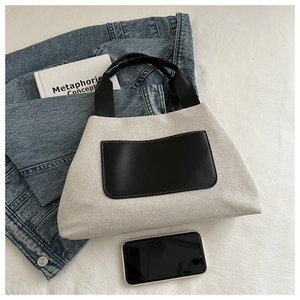 Top view of two-tone canvas bucket bag with black leather handles and interior space detail