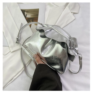 Detail of silver metallic pleated cloud bag featuring glossy ruffles and thin shoulder strap