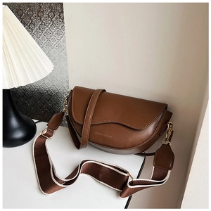 Detail of a dark brown faux leather saddle bag with striped strap and gold buckle