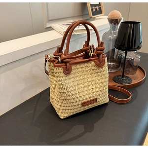 Detailansicht des geknoteten Ledergriffs und Riemens an dieser geflochtenen Strohtasche