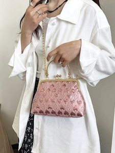 Pink heart pattern evening bag with metal handle and gold chain strap in stylish display