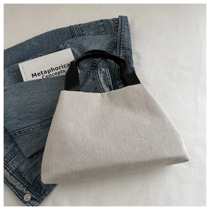 Close-up of minimalist knit tote bag with black leather handles and woven texture details