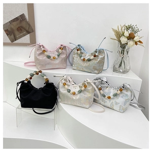 Détail de mini sacs nuage avec motifs floraux et poignées en perles élégantes