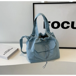 Détail du sac à cordon en nylon bleu clair montrant la texture mate et le design de l'anse