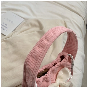 Close-up of pink corduroy handbag with white organza bow and drawstring detail