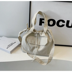Détail du sac seau en toile crème minimaliste avec cordon et poche avant à rabat
