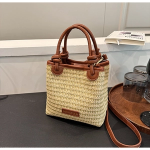 Detail der handgeflochtenen Strohtasche mit Ledergriffen und Marken-Logo-Schild
