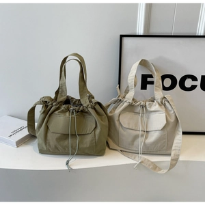 Détail de sacs seaux en nylon olive et beige avec cordon de serrage et poche à rabat avant