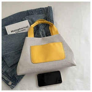 Close-up of canvas bucket bag with yellow leather accents on fabric background