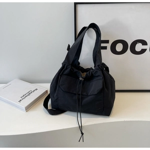 Détail du sac seau en nylon noir avec fermeture à cordon et poche frontale à rabat
