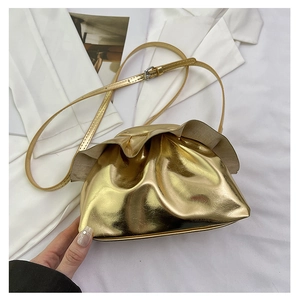 Detail of metallic gold pleated pouch bag with slim shoulder strap on fashion magazine