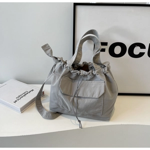 Détail du sac à bandoulière gris en nylon avec cordon de serrage et poche frontale