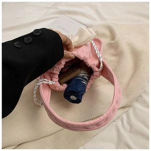 Pink corduroy bag interior showing capacity with a phone, umbrella, and cute white bow