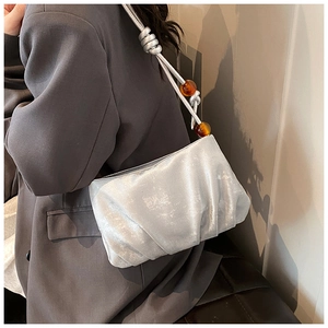 Detalle del bolso de nube plateado plisado con correas anudadas y cuentas de ámbar