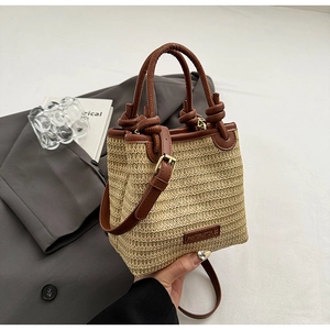 Detailansicht der gewebten Stroh-Beuteltasche mit Ledergriffen und Logo-Patch im Retro-Look