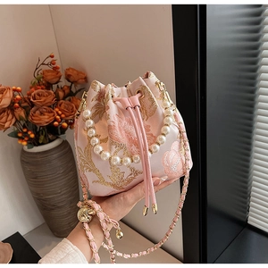 Close-up of floral embroidery and pearl handle on a pink bucket bag for women
