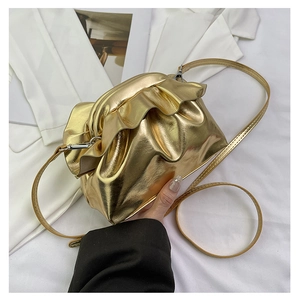 Detail of gold metallic mini crossbody bag with ruffled pleats and slim strap