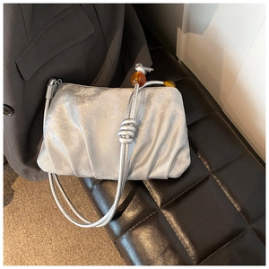 Detalle de bolso nube plisado plateado con cuentas de ámbar en banco de cuero