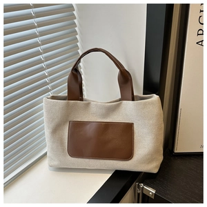 Detail of canvas bucket bag with brown faux leather pocket and elegant light shadows