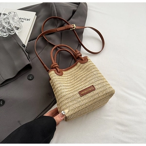 Detail der handgeflochtenen Strohtasche mit braunen Ledergriffen und Knotenakzenten