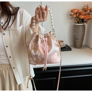 Detail of pink satin bucket bag with floral embroidery and elegant pearl handle