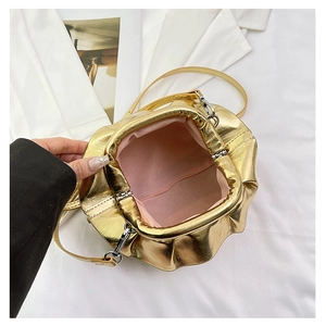 Detail view of gold cloud bag with pink lining, metallic frame, and slim strap