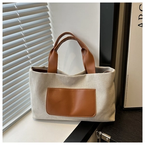 Detailed macro view of the cream canvas tote bag with brown faux leather pocket details