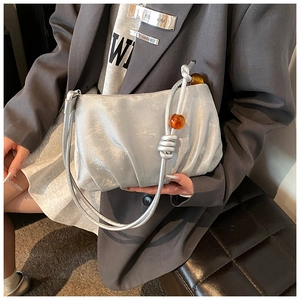 Detalle del bolso plisado plateado con cuentas de ámbar y textura metálica moderna