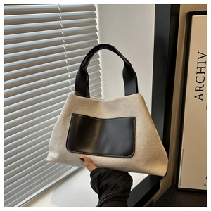 Detailed texture of beige canvas bucket bag with black leather pocket and strap