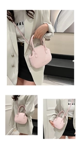 Detail of light pink shell-shaped crossbody bag with vintage metal frame and handles