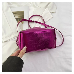 Macro detail of the metallic purple crossbody bag base with precise stitching and silver buckle