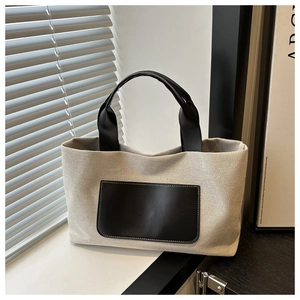 Detail of canvas tote bag showing black leather pocket and durable texture under sunlight