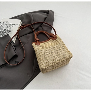 Detailansicht der gewebten Strohtasche mit braunen Ledergriffen und verstellbarem Schultergurt