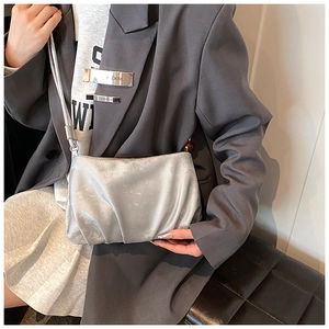 Primer plano de un bolso nube plisado plateado combinado con un blazer gris de moda