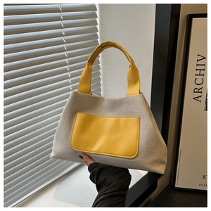 Close-up of canvas bucket bag with yellow leather trim and thick round handles