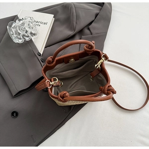 Detail der Stroh-Eimertasche mit braunem Lederbesatz, Reißverschlussfach und Knotengriffen