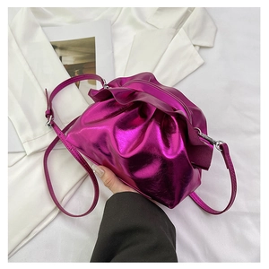 Close-up of bright pink metallic cloud bag featuring ruched texture and slim strap