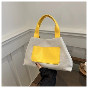 Detail of the cream canvas bucket bag with bright yellow PU leather handle and front pocket