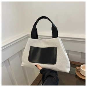 Detail of canvas bucket bag with black faux leather handles and front pocket decoration