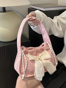 Pink corduroy crossbody bag with cream silk bow detail and drawstring closure