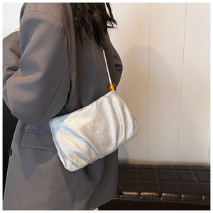 Detalle del bolso de hombro plisado plateado con acabado metálico y cuenta de ámbar