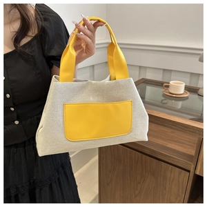 Detail of woven fabric bucket bag with yellow leather handles and front pocket