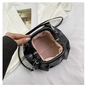 Detail view of black cloud bag with metal frame closure and soft pink fabric lining