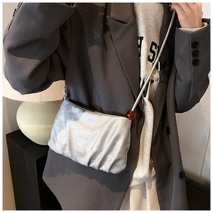 Primer plano del bolso nube plisado plateado con cadena metálica y detalle de cuenta