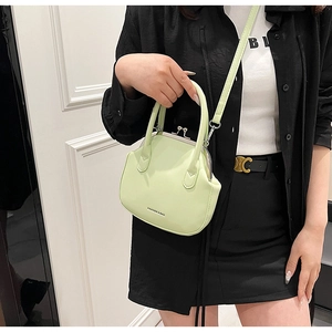 Detail view of pistachio green shell bag with metal clasp and leather handle